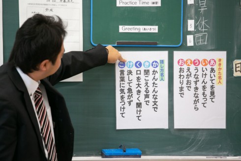 写真、黒板を指差して英語の授業をする先生