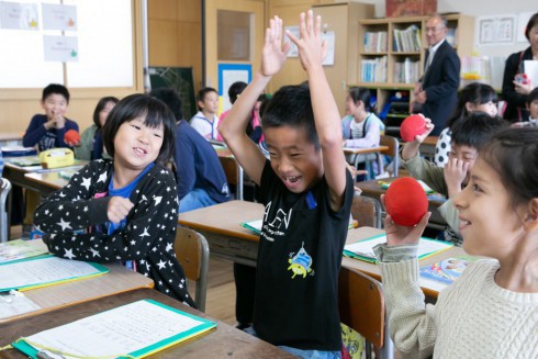 写真、両手を上げて英語の授業を楽しむ子ども