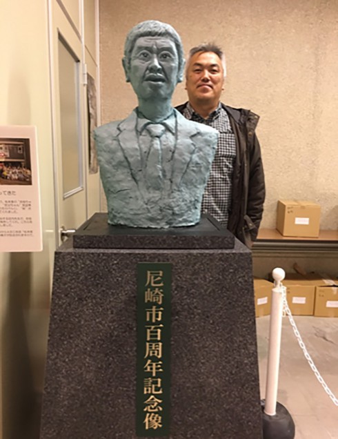 写真、テレビ撮影で使用された松本人志さんの銅像と記念撮影する槌賀さん