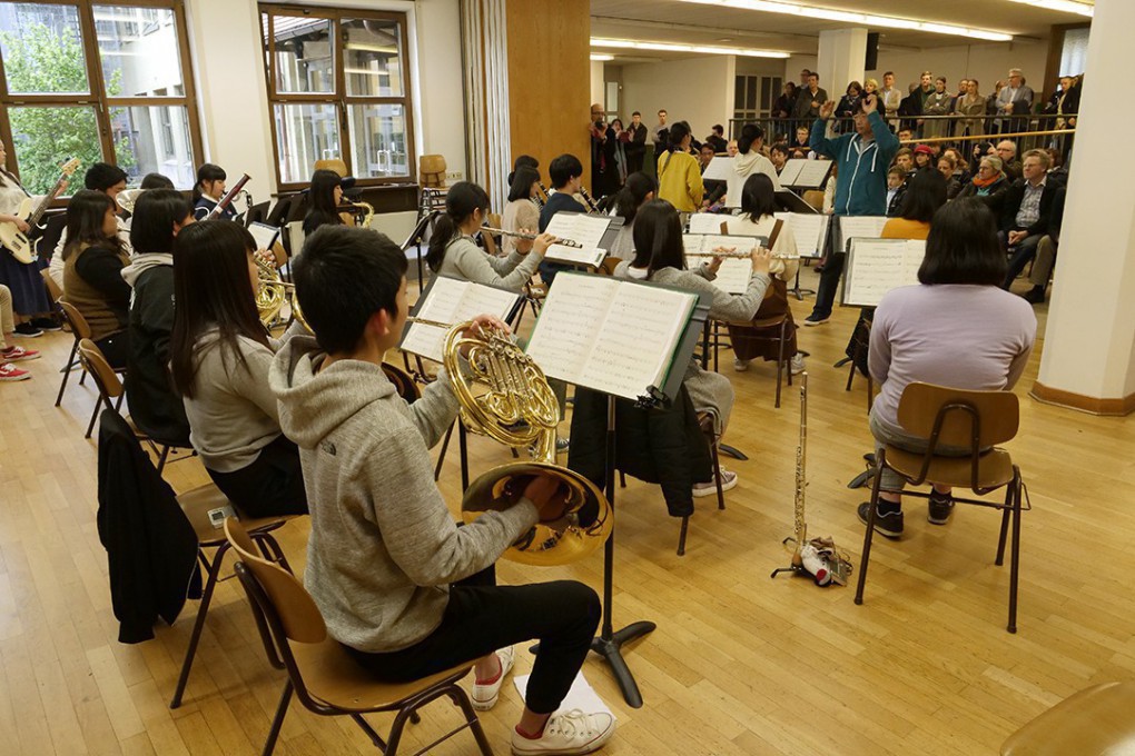 写真、感謝の集いでホストファミリーの前で演奏する尼崎の高校生たち
