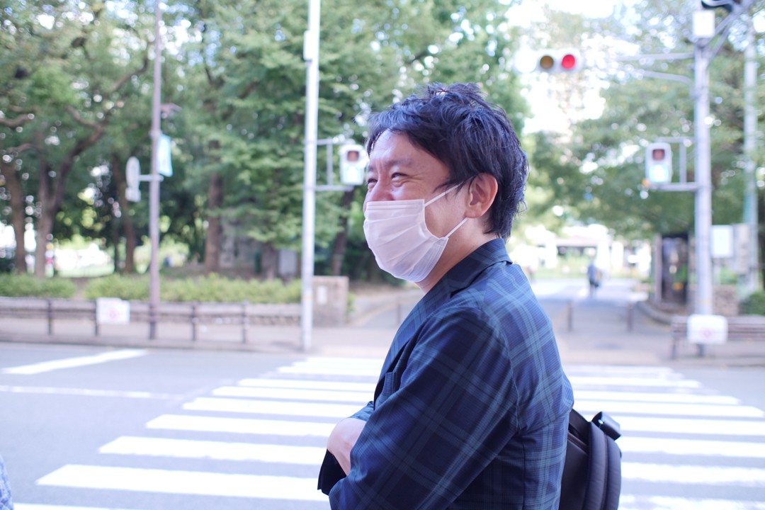写真、尼崎中央商店街入り口で取材を受ける成海さん