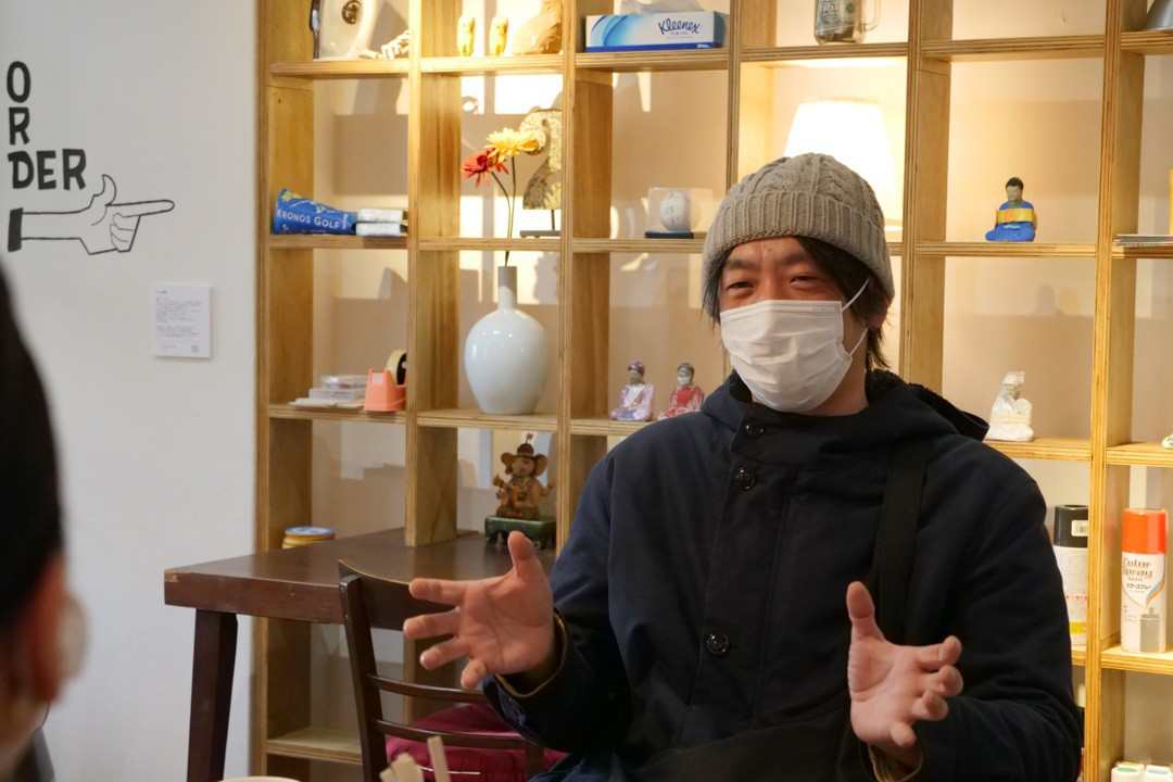 写真、カフェ「パイナワーフ」で取材を受ける前田さん
