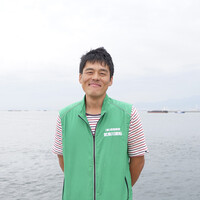 写真、海をバックに笑顔の宮本さん