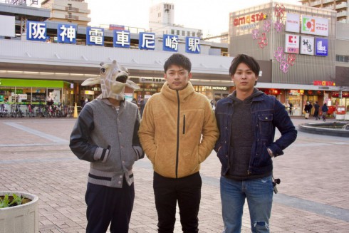 写真、阪神尼崎駅前に並ぶ編集部の３人。