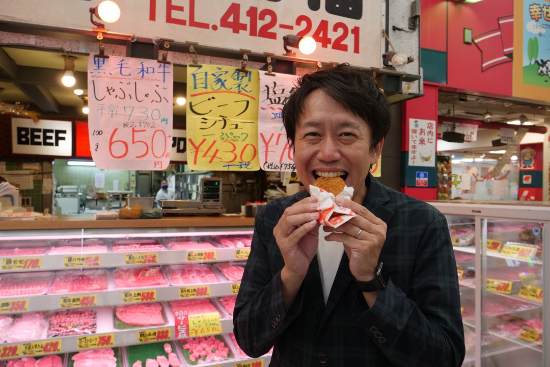 写真、コロッケを食べる成海さん