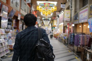 写真、商店街を歩く成海さんの後ろ姿