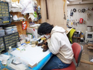 写真、工房内でギターを製作する職人