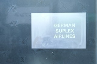 写真、制作拠点の扉に貼られた「GERMAN SUPLEX AIRLINES」ステッカー
