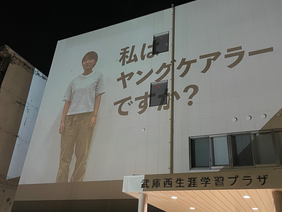 写真、武庫西生涯学習プラザの壁に投影されたヤングケアラー啓発動画