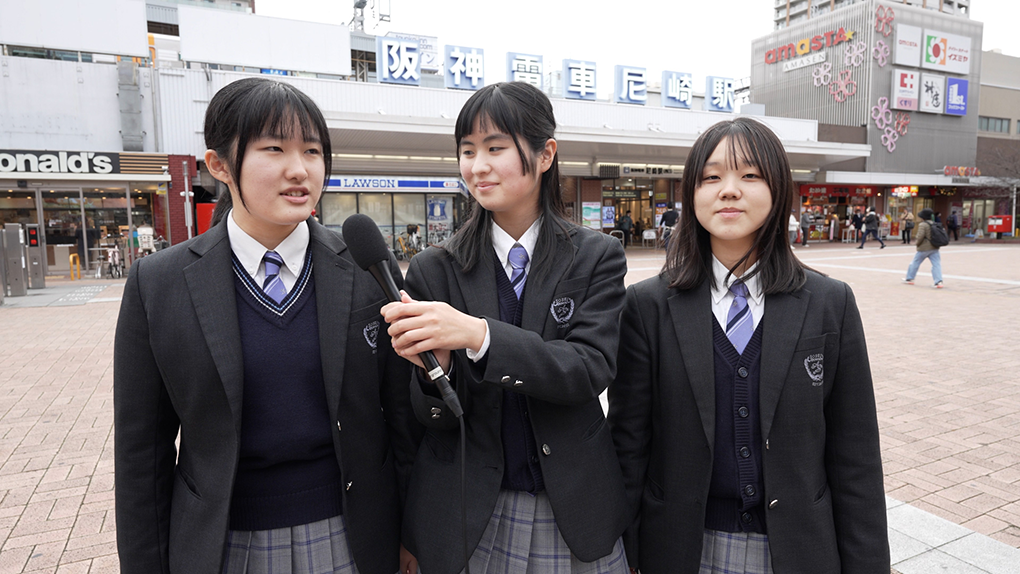 阪神尼崎駅の前でレポートする高校生