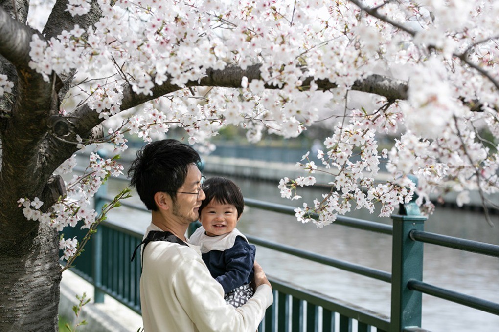 川沿いの桜の木の下に立つ親子