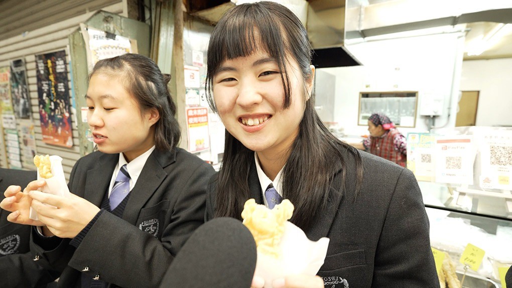 店先で食レポする高校生