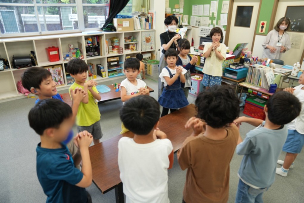 室内で輪になって体操をするこどもクラブの子どもたち