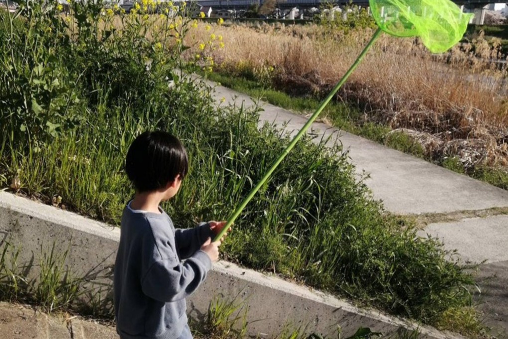 写真、川の河川敷に虫とり網を持って遊びにきた鍬さんの子ども