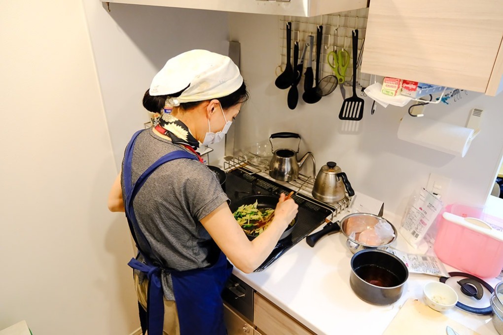 写真、キッチンで料理をするヘルパー