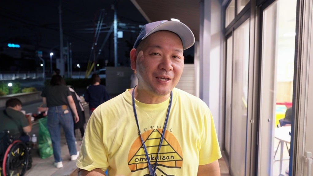 写真、おむかいさんぷろじぇくと代表が話す様子