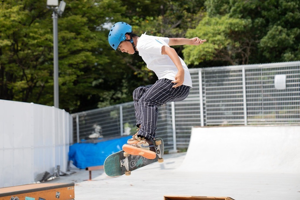 写真、スケートボードを回転させるトリックを披露する吉金さん