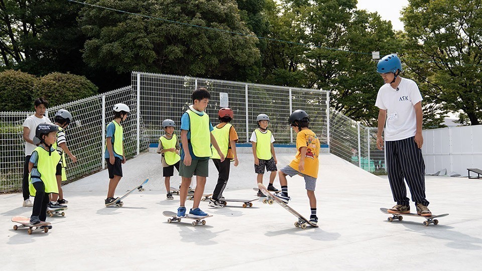 写真、板に乗せる足の位置を教えてもらう様子