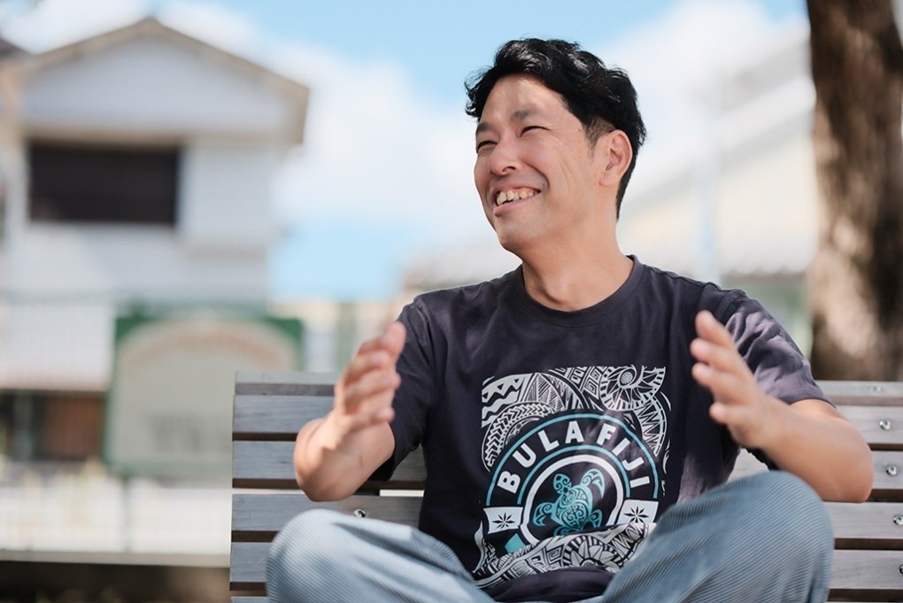 写真、公園のベンチに座って取材を受ける、永崎裕麻さん