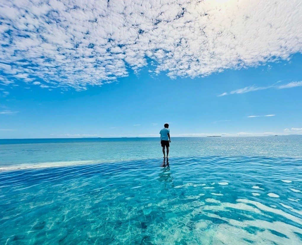 写真、フィジーのマラマラ島にて、まるで海とつながっているようなプールに佇む永崎さん