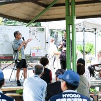 ランチミーティングで発表する男性（中央））