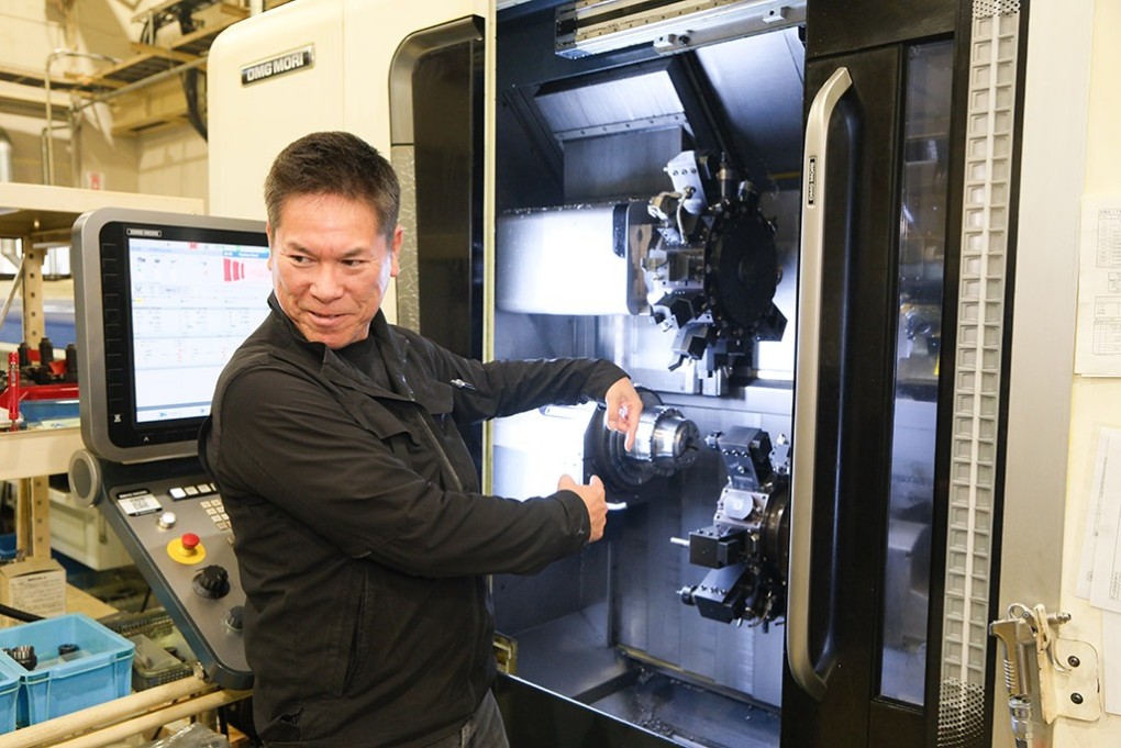 写真、機械の前に立つ金指さん