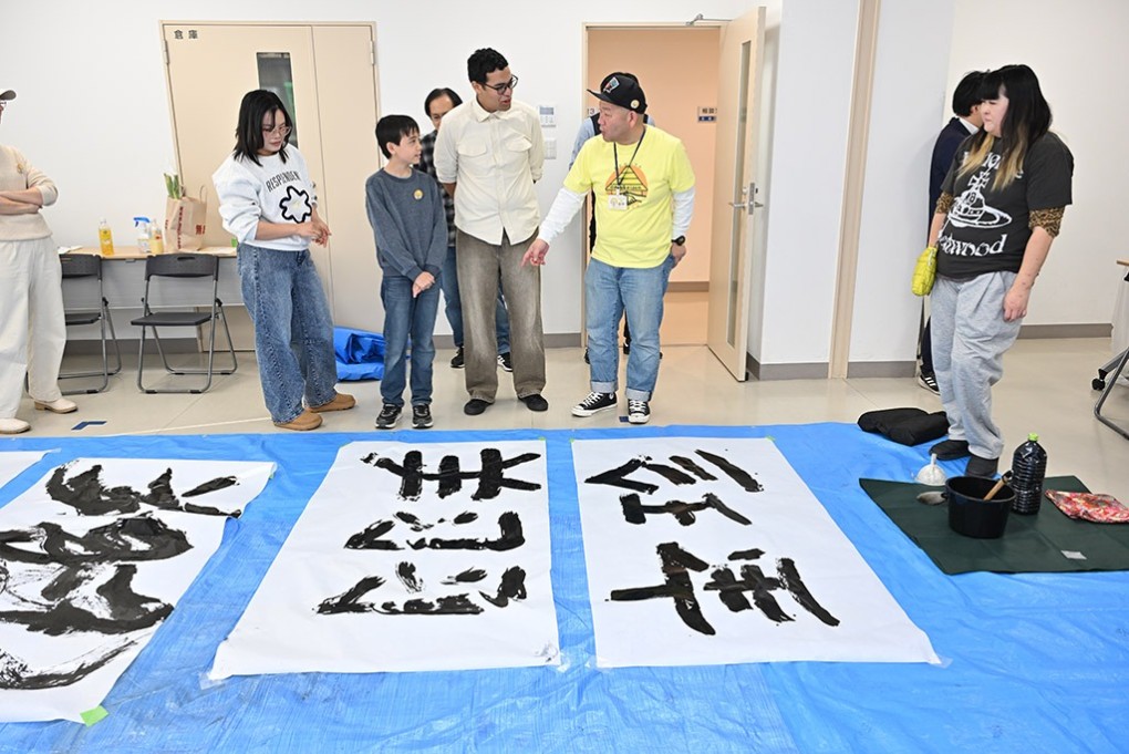 写真、大きな書を前に参加者と話す大山さん