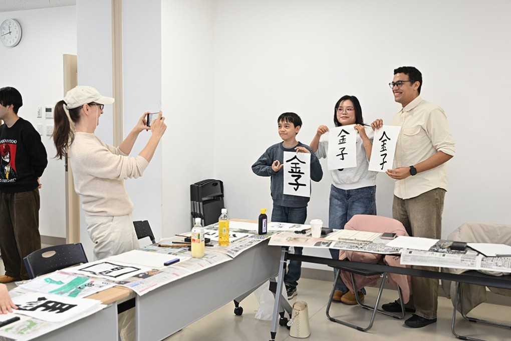 写真、自分の書いた書を手に記念撮影する参加者たち