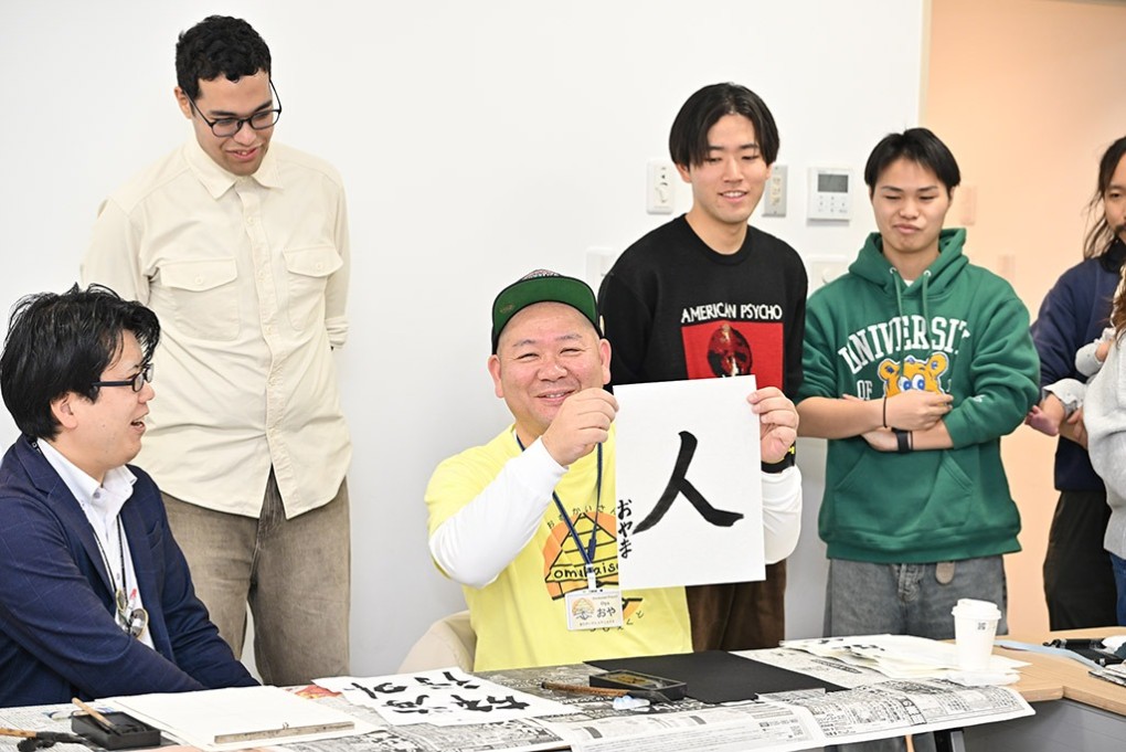 写真、人と書いた書を持つ大山さん