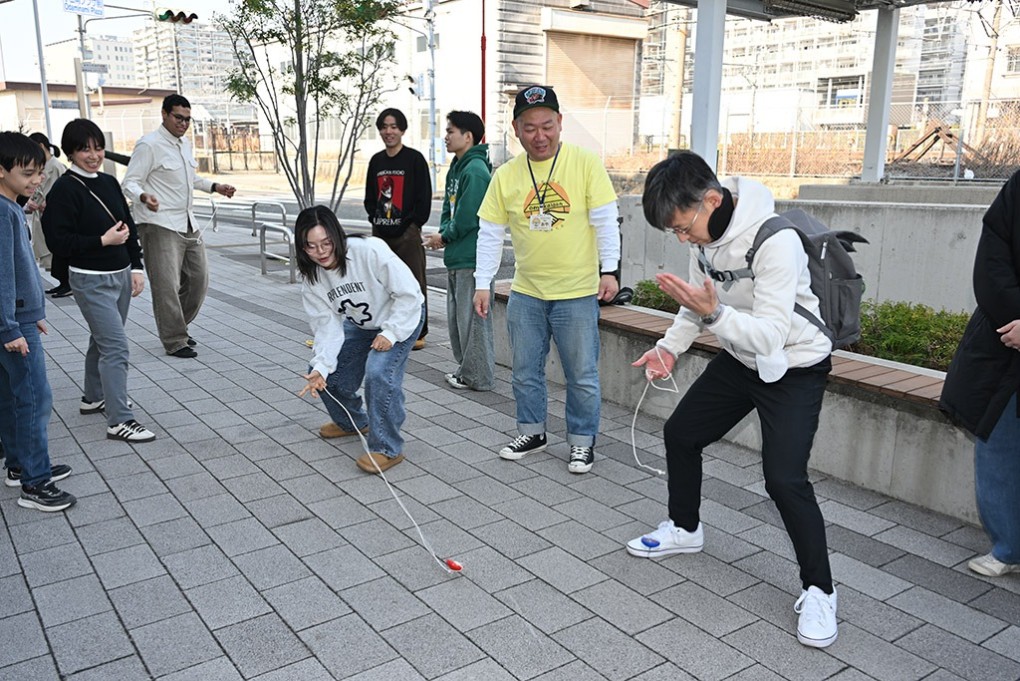 写真、コマ回しに挑戦する参加者たち