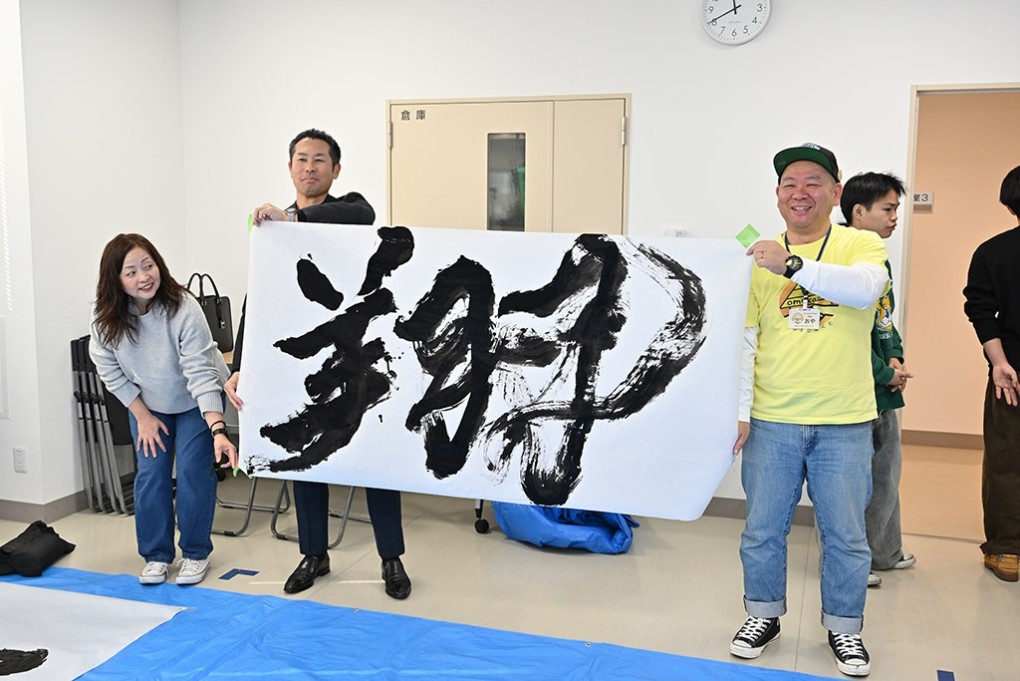 写真、右は、しかたさんの書の翔を手にした大山さん