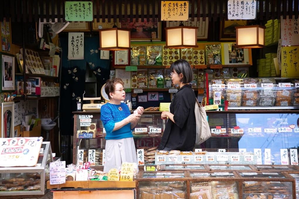 写真、手焼き煎餅屋、中田屋での様子。筆者と店主が談笑している。